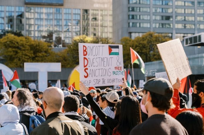 A demonstrator holds a sign supporting the BDS movement at a Palestine solidarity rally in Toronto. (Shutterstock)