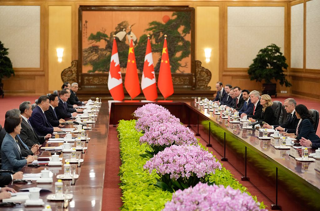 Heads of State from different nations seated at a large banquet table with flags and a painted screen in the background