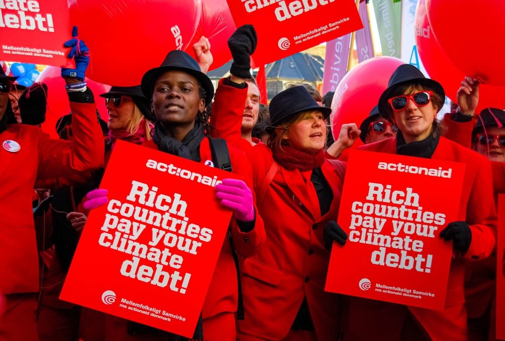 A group of protestors with signs reading, "Rich countries, pay your climate debt!"