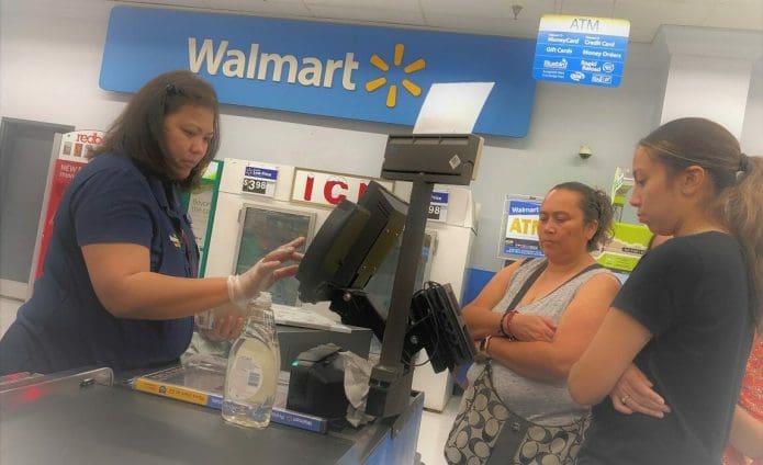 Photo of shoppers and a store clerk in a checkout line at a Walmart