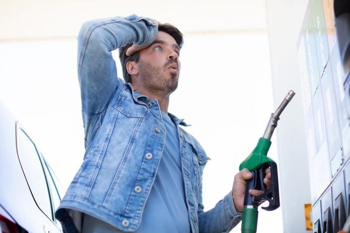A man with a shocked expression at the gas pump.