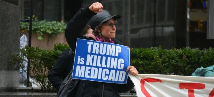 A demonstrator holds a sign reading: "Trump is killing Medicaid"