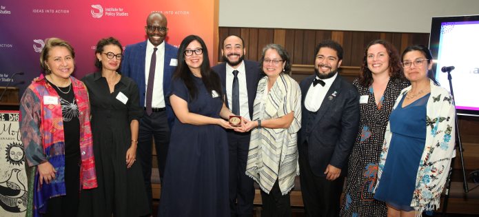 Members of Unidos MN accept the 2026 LM Human Rights Award. Emilia Gonzalez Avalos is fourth from left, holding the award. IPS Executive Director Tope Folarin is third from left. (Photo by Rick Reinhard for IPS)